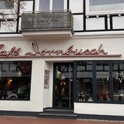 Außenansicht Fachwerkgebäude mit Café Dornbusch, breite Fensterfront, Leuchtreklame und großer Eistüte außen.