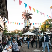 Odonien Ein lebhafter Markt mit bunten Wimpeln, fröhlichen Menschen und kreativen Skulpturen.A lively market with colorful bunting, cheerful people and creative sculptures.