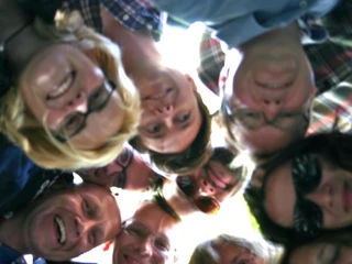 Auf geht's - Team Köln Gruppe von Personen steht im Kreis und schaut nach unten in die KameraGroup of people standing in a circle and looking down into the camera