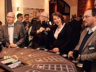 Casino Vinophil. Black-Jack Tisch Gruppe von Personen genießt geselliges Beisammensein an einem Spieltisch bei einem Event im Innenraum.</p>Group of people enjoying socializing at a gaming table at an indoor event.</p> <p