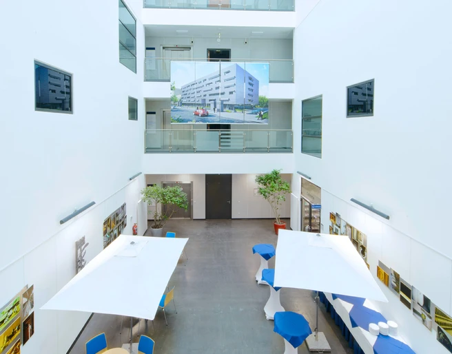 ZMMK-Foyer Modernes, lichtdurchflutetes Atrium mit Glaskuppel und mehreren Etagen, dekoriert mit Tischen.Modern, light-flooded atrium with glass dome and several floors, decorated with tables.