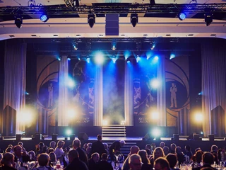 Chariot_Maritim_005 Bühne mit blauem Licht, Showtreppe, rundes Publikum; Gala-Event-Stimmung in elegantem Saal.Stage with blue light, show stairs, round audience; gala event atmosphere in an elegant hall.