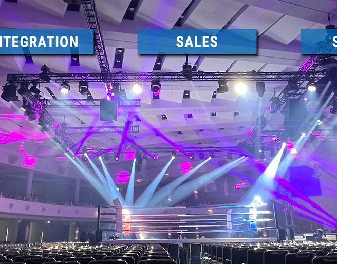KKT_HEADER_2024.jpg Eine spektakulär beleuchtete Eventhalle mit leeren Sitzreihen und einem Boxring im Zentrum.A spectacularly illuminated event hall with empty rows of seats and a boxing ring in the center.