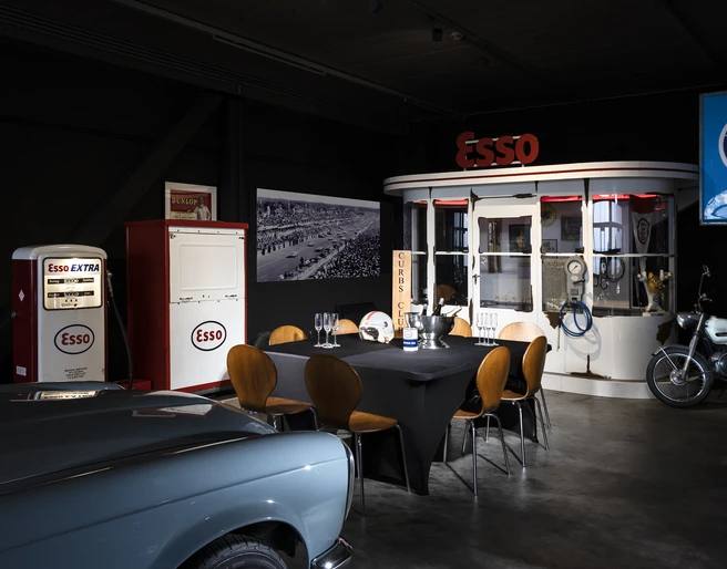 04_CC_PrivateDinner.jpg Retro-Essenzapfsäule und Esso-Diner mit Oldtimer-Motorrad in einem nostalgischen Ausstellungsraum.Retro petrol pump and Esso diner with vintage motorcycle in a nostalgic showroom.