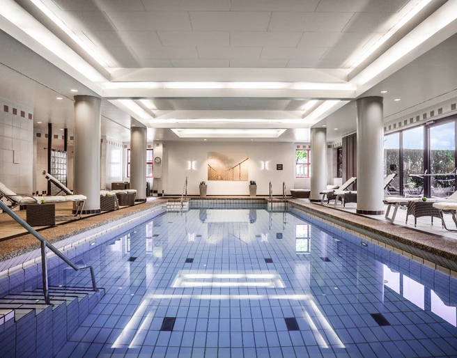 Puls fittness club Eleganter Innenpool mit Liegen, modernen Säulen und großen Fenstern für eine entspannte Atmosphäre.</p>Elegant indoor pool with loungers, modern columns and large windows for a relaxed atmosphere.