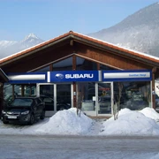 Auto Heigl Farchant Frontansicht eines Hauses mit dem Schild Subaru, Günther Heigl. Davor steht ein Auto, daneben befinden sich ein paar Schneehaufen