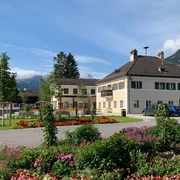 Rathaus-Fundbüro Farchant Rathaus Farchant, davor Blumenbeet im Hintergrund Bäume, der Kramer und weiter hinten das Wettersteingebirge mit Zugspitze