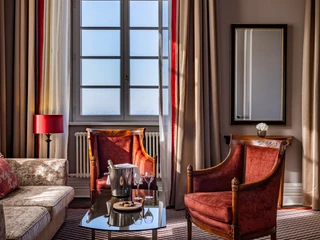 Dom Suite Ein stilvoll eingerichtetes Wohnzimmer mit roten Sesseln, Sofa und einem Fenster, das Tageslicht hereinlässt.A stylishly furnished living room with red armchairs, sofa and a window that lets in natural light.