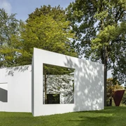 Sculpture park Weiße, rechteckige Skulptur im grünen Park, umgeben von hohen Bäumen, zeigt ein Fenster.White, rectangular sculpture in a green park, surrounded by tall trees, showing a window.
