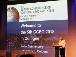 Global Conference on Economic Geography Welcome-Banner und Redner auf der World Conference, wirtschaftsgeografisches Event in Köln 2018.Welcome banner and speakers at the World Conference, economic geography event in Cologne 2018.
