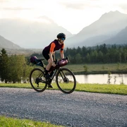 Eine Gravelbikerin fährt auf einem Feldweg entlang des Geroldsees in der Zugspitz Region.