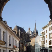 2020-02 Dom vom Hof Blick auf den Aachener Dom und den Hof unter blauem Himmel durch einen Torbogen hindurch.