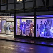 Beleuchtetes Modegeschäft Finkhäuser in Vlotho, mit Schaufensterpuppen in bunter Kleidung bei Nacht.