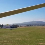 Flugplatz in Ober-Mörlen Flugplatz in Ober-Mörlen mit mehreren Segelfliegern am Boden. Im Hintergrund ist der Große Feldberg zu sehen.