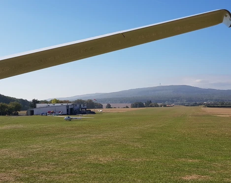 Flugplatz in Ober-Mörlen Flugplatz in Ober-Mörlen mit mehreren Segelfliegern am Boden. Im Hintergrund ist der Große Feldberg zu sehen.
