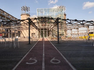 Museumsterrasse (21).jpg Moderner Pavillon mit Glasfassade, flankiert von zwei Türmen und umgeben von Metallstruktur.</p>Modern pavilion with glass façade, flanked by two towers and surrounded by metal structure.</p> <p