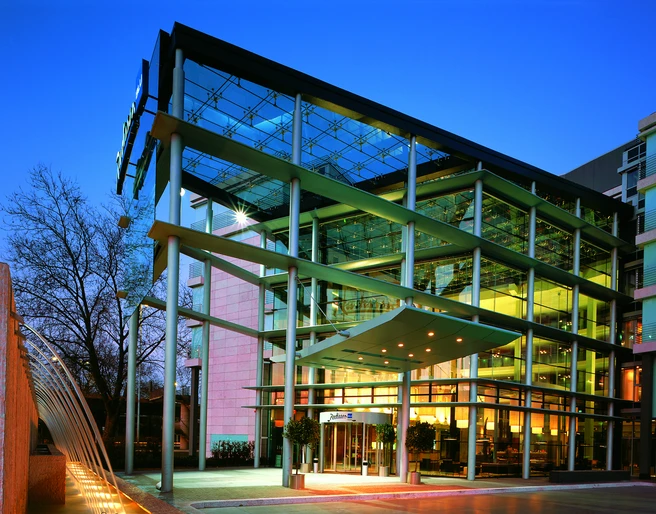 Exterior Modernes Gebäude mit Glasfassade, beleuchtet in der Dämmerung, zeigt architektonische Eleganz.</p>Modern building with glass façade, illuminated at dusk, shows architectural elegance.</p> <p