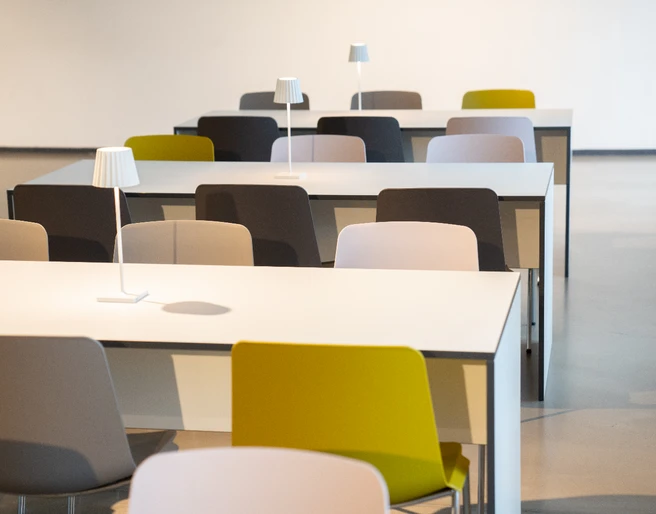 Mietmöbel Tische mit bunten Stühlen und Tischlampen in modernem, minimalistischem Design in einem hellen Raum.Tables with colorful chairs and table lamps in a modern, minimalist design in a bright room.