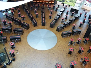 miro-110-schwarz3.jpg Runder Saal mit Holzboden, schwarzem Mobiliar und rot-grün karierten Tischdecken aus der Vogelperspektive.Round hall with wooden floor, black furniture and red and green checkered tablecloths from a bird's eye view.
