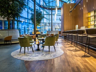 Bar Modernes Bar-Interieur mit eleganten Stühlen und warmer Beleuchtung vor einer hohen Glasfassade.Modern bar interior with elegant chairs and warm lighting in front of a high glass façade.