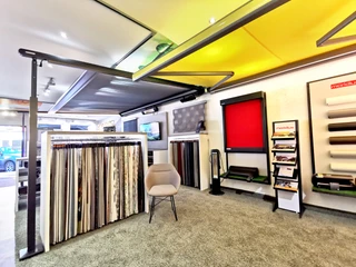 Raumausstattung Weist Ein heller Ausstellungsraum mit Sonnenschutzprodukten, Stoffmustern und modernen Sitzgelegenheiten.