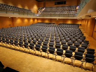 Großer Saal Ein großer, leerer Konzertsaal mit zahlreichen Stuhlreihen und Holzverkleidung an den Wänden.</p>A large, empty concert hall with numerous rows of chairs and wood paneling on the walls.</p> <p