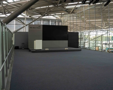 Lounge (4 von 9).jpg Eine leere Bühne im modernen Flughafen mit Glaswänden im Hintergrund.An empty stage in a modern airport with glass walls in the background.