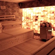 Sauna in der Birkensauna.jpg Eine Holzsauna mit Wänden aus beleuchteten Salzziegeln schafft eine entspannende und warme Atmosphäre.