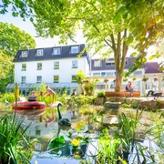 Gartenhotel Fettehenne in Erkrath Gartenhotel Fettehenne in Erkrath mit Teich, grüner Umgebung und moderner weißer Fassade.