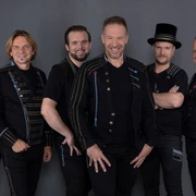 Höhner Sechs lächelnde Männer in schwarzer Kleidung und festlichem Design posieren vor grauem Hintergrund.</p>Six smiling men in black clothing and festive designs pose in front of a gray background.</p> <p