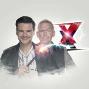 Zaubertrixxer Jung und Thomaszauberer mit Funkenstab, hinter ihm ein großes rotes X, beide lächeln.Young and Thomas Wizard with sparking staff, behind him a big red X, both smiling.