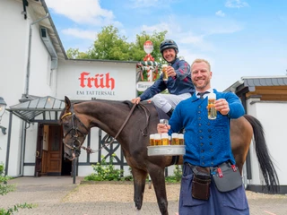 FRÜH-Rennbahn+Motiv3385+final.jpg Ein Mann auf einem Pferd und ein Kellner mit Bier vor einem traditionellen Bierhaus.</p>A man on a horse and a waiter with beer in front of a traditional beer house.</p> <p