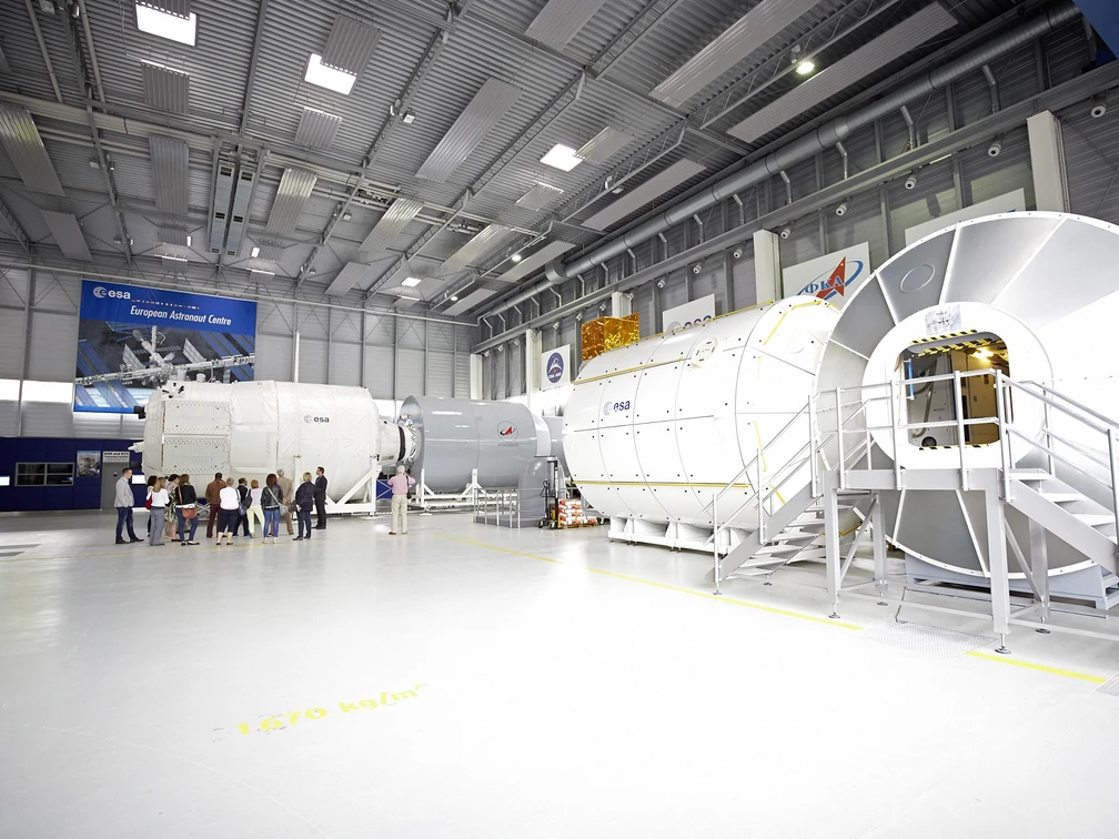 Europäisches Astronautenzentrum Mockup von Raumfahrtmodulen in einem modernen, großen Hochtechnologielabor mit Besuchern und ESA-Logo.Mockup of space modules in a modern, large high-tech laboratory with visitors and ESA logo.