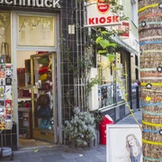 Belgian Quarter in Cologne Ein traditioneller Kiosk in Köln bietet farbenfrohe Waren aller Art. Ein Baum vor dem Laden ist mit bunten Bändern und Sternen dekoriert, was der Straße ein lebendiges Flair verleiht.A traditional kiosk in Cologne offers colorful goods of all kinds. A tree in front of the store is decorated with colorful ribbons and stars, giving the street a lively flair.
