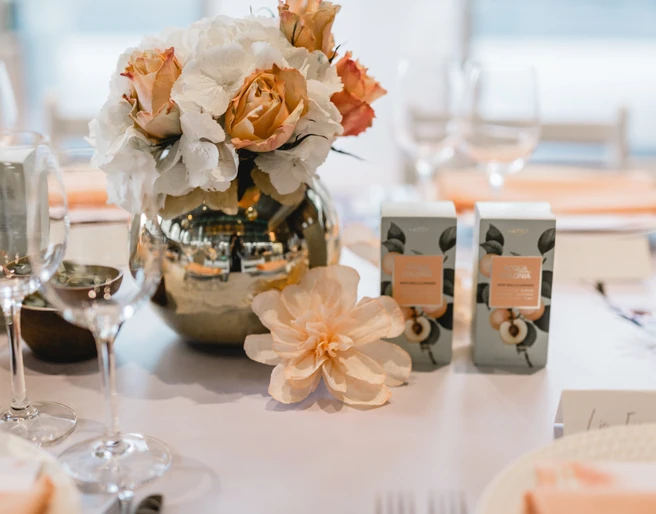 4711 Duftmenü Blumenvase mit Rosen und weißen Blumen auf einem elegant gedeckten Tisch, umgeben von Weingläsern.Flower vase with roses and white flowers on an elegantly laid table, surrounded by wine glasses.