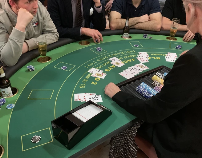Black Jack 01 Poker-Spieler an rundem grünen Tisch mit Karten, Getränken und Chips in geselliger Atmosphäre.Poker players at a round green table with cards, drinks and chips in a convivial atmosphere.
