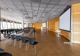 Raum 1-3  Ein moderner Konferenzraum mit leeren Stuhlreihen und zwei großen Bildschirmen.</p>A modern conference room with empty rows of chairs and two large screens.</p> <p