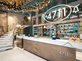 Dufthaus_Interior_3.jpg Eleganter 4711-Laden mit Weihnachtsschmuck, Regale voller Parfümflaschen, geschwungene Treppe.Elegant 4711 store with Christmas decorations, shelves full of perfume bottles, curved staircase.