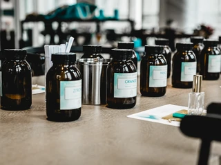 4711 Duftseminar 2 Braune Glasflaschen mit Duftölen und Zutaten auf einem Tisch in einem modernen Labor.Brown glass bottles with scented oils and ingredients on a table in a modern laboratory.