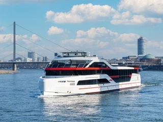 Rhein Galaxie Das Luxus-Ausflugsschiff "RheinGalaxie" fährt auf dem Rhein, mit Stadt und Brücke im Hintergrund.The luxury excursion boat "RheinGalaxie" sails on the Rhine, with the city and bridge in the background.