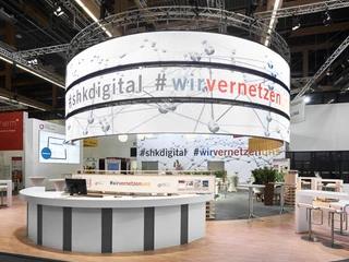 SHK-Messestand Messestand mit großem, rundem LED-Bildschirm, zeigt digitale Hashtags, moderne Präsentation.</p>Exhibition stand with large, round LED screen, displays digital hashtags, modern presentation.</p> <p