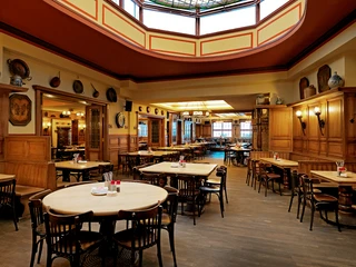 Brauhaus FRÜH am Dom, Wappesaal Ein traditionelles Wiener Gasthaus mit Holzvertäfelungen und gemütlicher Beleuchtung.A traditional Viennese inn with wood paneling and cozy lighting.