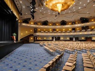 Saal Maritim Ein eleganter, leerer Theatersaal mit goldenen Details und einem großen Kronleuchter.An elegant, empty theater hall with golden details and a large chandelier.