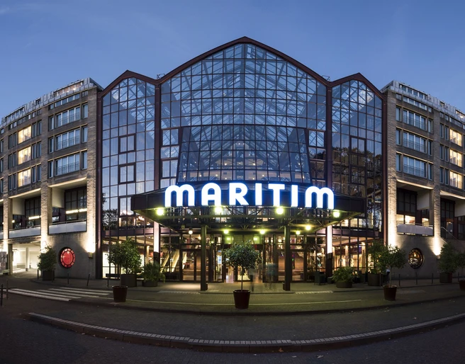 Maritim Hotel Köln Das Maritim Hotel mit Glasfassade und beleuchtetem Eingang in der Abenddämmerung.</p>The Maritim Hotel with its glass façade and illuminated entrance at dusk.</p> <p
