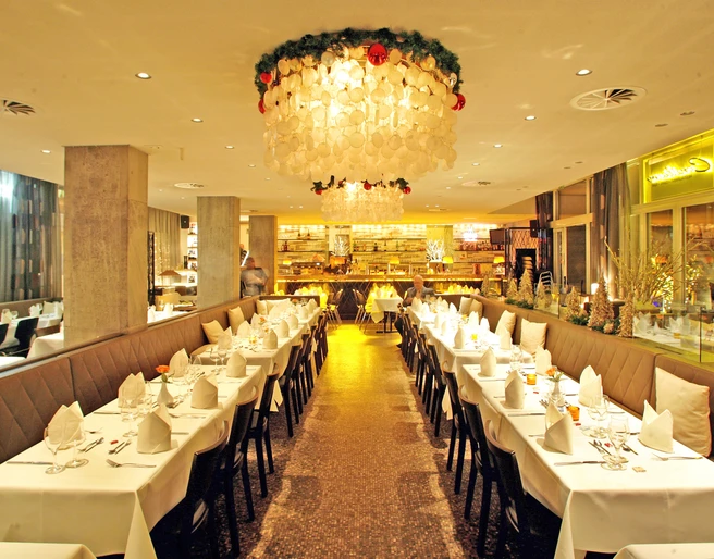 00-CONSILIUM-Event-Restaurant-Innenraum Elegantes Restaurant mit festlich gedeckten Tischen und strahlendem Kronleuchter in gemütlichem Ambiente.</p>Elegant restaurant with festively laid tables and a radiant chandelier in a cozy ambience.