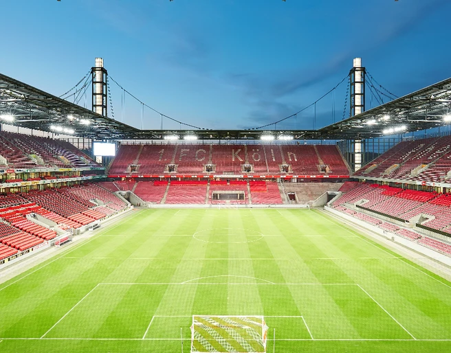 Innenbild RheinEnergie Stadion Innenansicht eines leeren Fußballstadions mit grünem Rasen und Sitzreihen in Rot.</p>Interior view of an empty soccer stadium with green grass and rows of seats in red.</p> <p