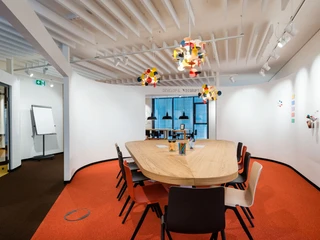 Denkfabrik im Innovation Center.jpg Moderner Konferenzraum mit ovalem Holztisch, bunten Stühlen und Designerleuchten auf rotem Teppich.</p>Modern conference room with oval wooden table, colorful chairs and designer lights on a red carpet.</p> <p
