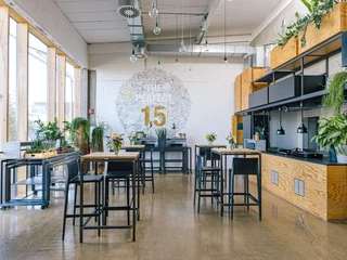 DEINspeisesalon Industrie-chic Café mit hohen Tischen, Pflanzen und moderner Wanddekoration im hellen Raum.Industrial-chic café with high tables, plants and modern wall decorations in a bright room.