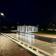 Fahrradstation am Dock Beleuchtete Fahrradstation mit überdachten Abstellplätzen an einer nassen Straße in der Nacht