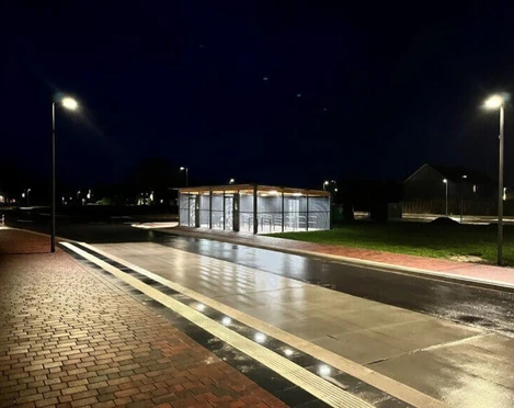 Fahrradstation am Dock Beleuchtete Fahrradstation mit überdachten Abstellplätzen an einer nassen Straße in der Nacht
